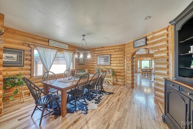 dining area with light wood finished floors, a wealth of natural light, and a textured ceiling