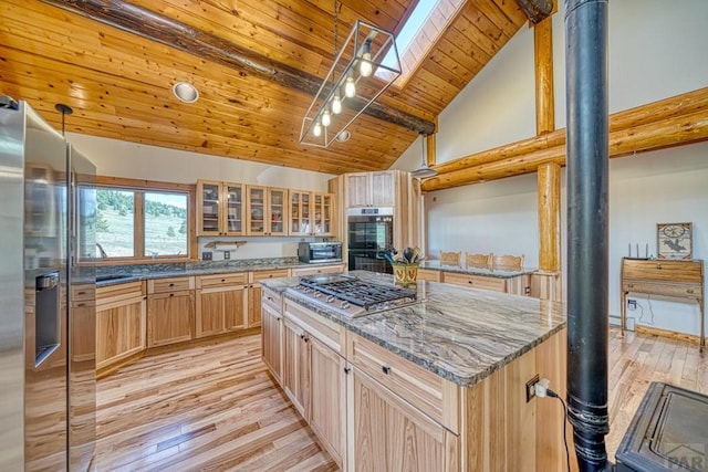 kitchen with stone countertops, wood ceiling, a kitchen island, glass insert cabinets, and stainless steel appliances