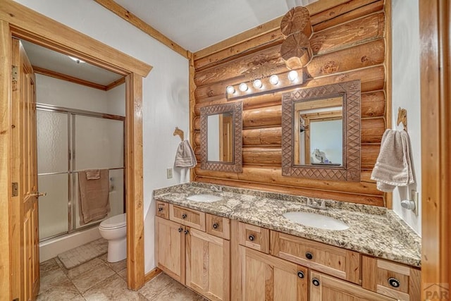 bathroom with double vanity, a stall shower, a sink, and toilet