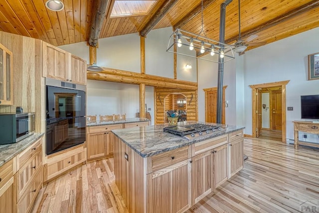 kitchen featuring glass insert cabinets, appliances with stainless steel finishes, light brown cabinetry, and a center island