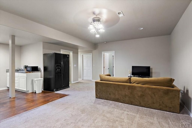 carpeted living area with baseboards and ceiling fan