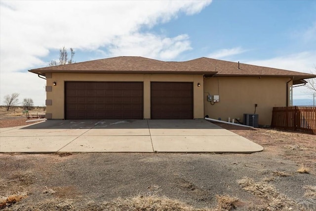 garage with concrete driveway, fence, and central AC