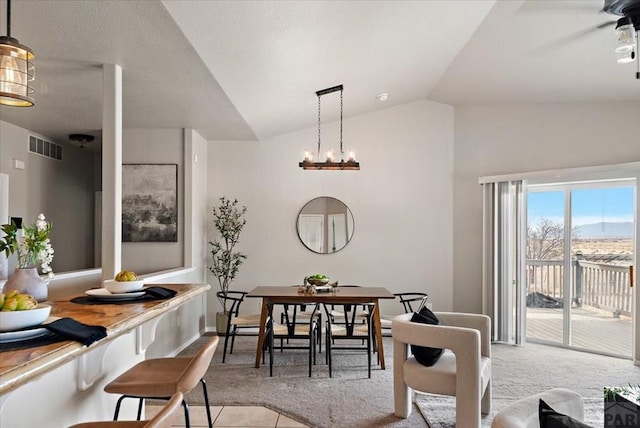 dining room with visible vents, light colored carpet, an inviting chandelier, and vaulted ceiling