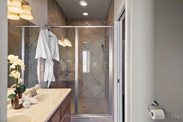 bathroom with a shower stall, double vanity, and a sink