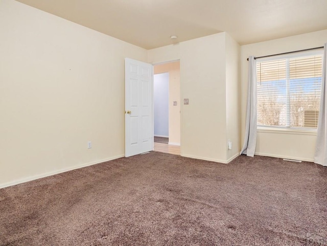 unfurnished room with carpet flooring and baseboards
