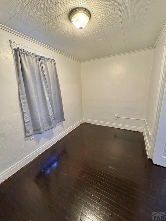 empty room with baseboards, dark wood-type flooring, and ornamental molding