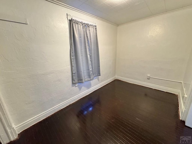 unfurnished room with dark wood-style floors, a textured wall, and baseboards