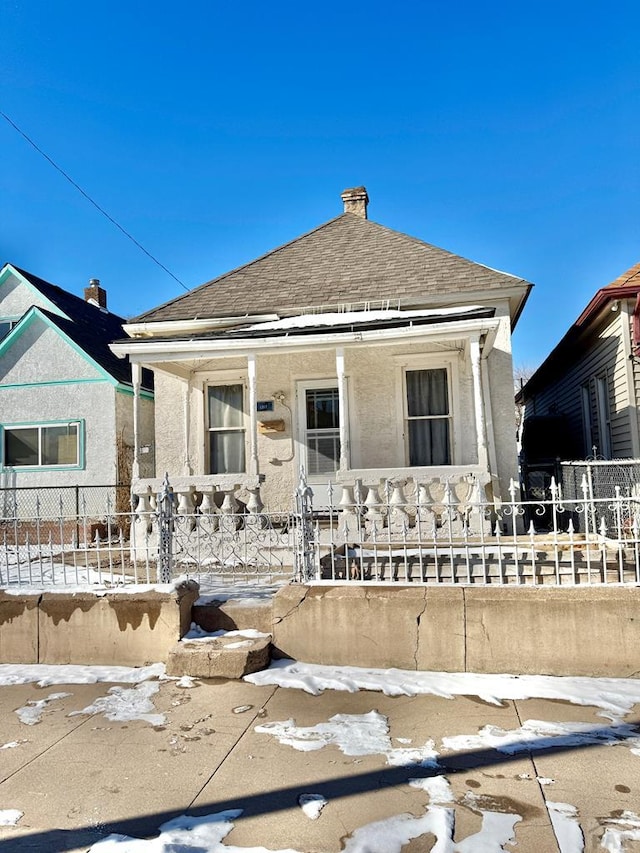 view of front of home featuring a fenced front yard, a shingled roof, and stucco siding