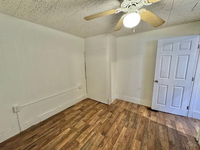 unfurnished room with a ceiling fan, dark wood-style flooring, and baseboards