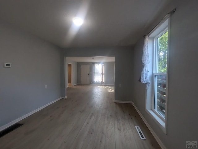 interior space with light wood-type flooring, plenty of natural light, visible vents, and baseboards