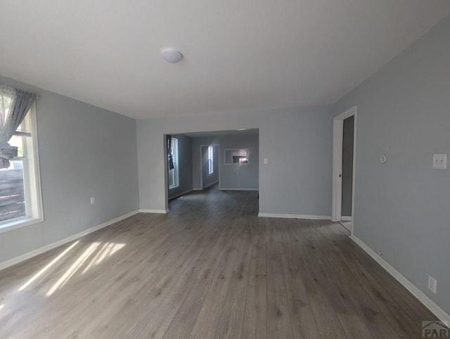 unfurnished living room with dark wood finished floors and baseboards