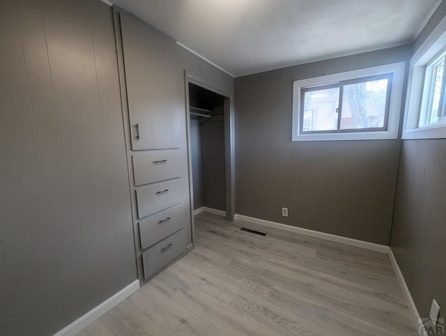 unfurnished bedroom with light wood finished floors, visible vents, and baseboards