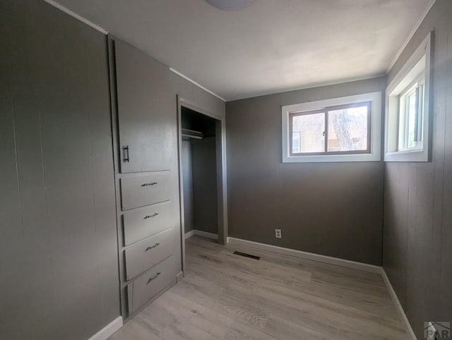 bedroom with light wood finished floors, baseboards, visible vents, and a closet