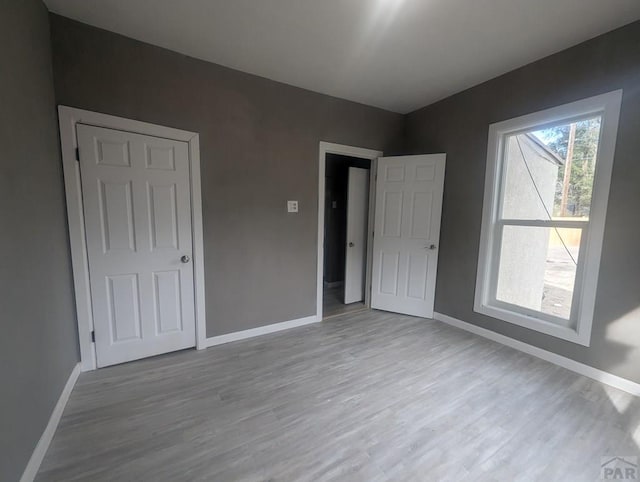 unfurnished bedroom with light wood-style flooring and baseboards