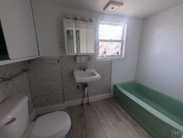 bathroom featuring a tub, toilet, and wood finished floors