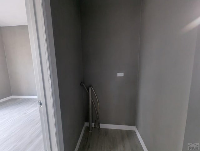 clothes washing area featuring wood finished floors and baseboards