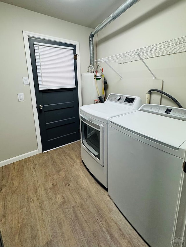 washroom with light wood-type flooring, washer and clothes dryer, gas water heater, baseboards, and laundry area