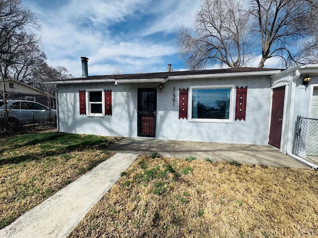 ranch-style home featuring stucco siding, a front yard, and fence