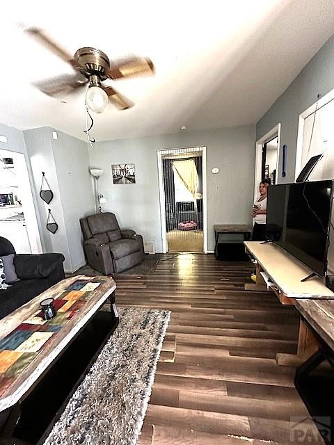 living area featuring dark wood-type flooring and a ceiling fan