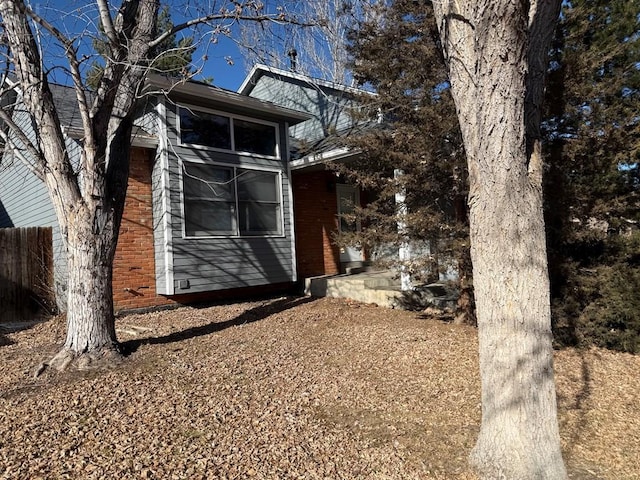 view of side of home featuring fence and brick siding