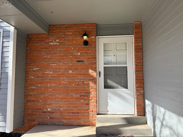 view of exterior entry featuring brick siding