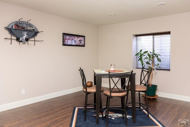 dining area featuring baseboards and dark wood-type flooring