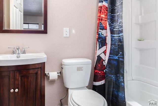 full bathroom featuring a textured wall, shower / bath combo with shower curtain, vanity, and toilet