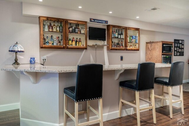 bar with dark wood-style floors, visible vents, built in microwave, and recessed lighting