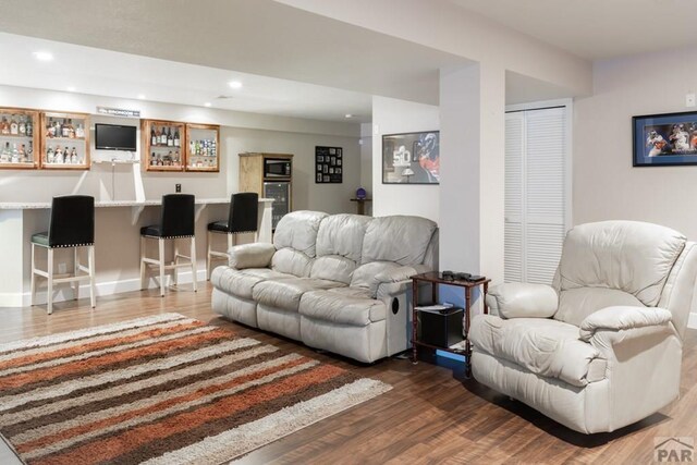 living area with recessed lighting, a bar, and wood finished floors