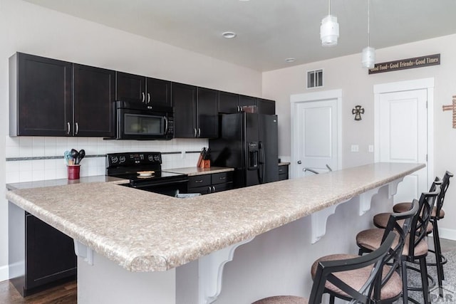 kitchen with dark cabinets, visible vents, light countertops, black appliances, and tasteful backsplash