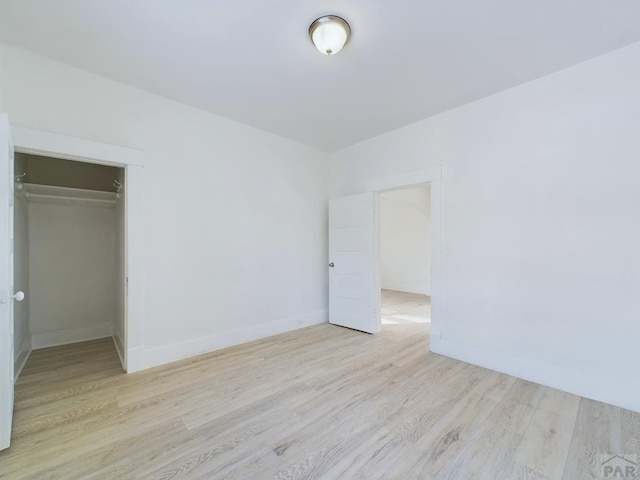 unfurnished bedroom featuring baseboards, a closet, and light wood-style floors