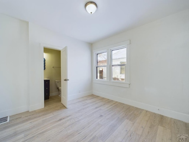 unfurnished room with light wood-style flooring, visible vents, and baseboards