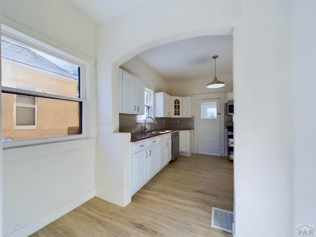 kitchen featuring visible vents, white cabinetry, dark countertops, glass insert cabinets, and pendant lighting