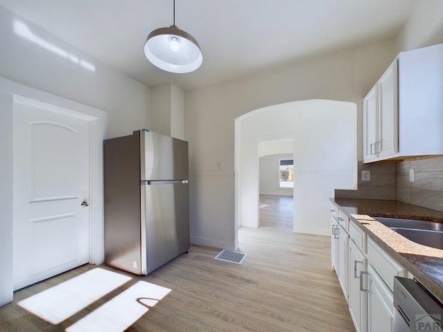 kitchen featuring dark countertops, visible vents, freestanding refrigerator, white cabinets, and dishwasher