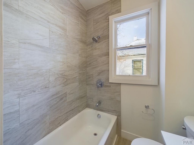 bathroom with baseboards, bathing tub / shower combination, and toilet