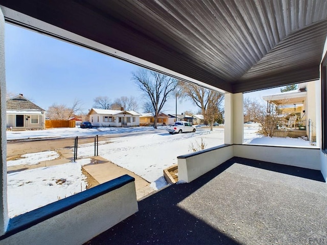 snow covered patio featuring a residential view