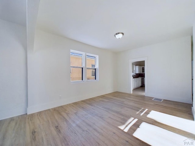 spare room with light wood-style flooring, visible vents, and baseboards