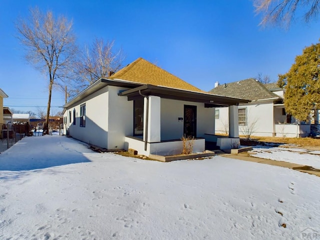 exterior space featuring covered porch, a shingled roof, fence, and stucco siding