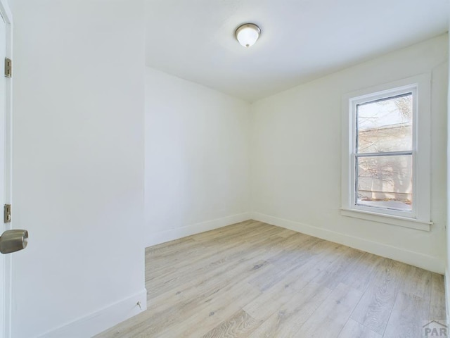 spare room featuring light wood-type flooring and baseboards