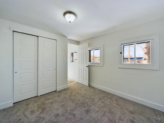 unfurnished bedroom with baseboards, a closet, and light colored carpet