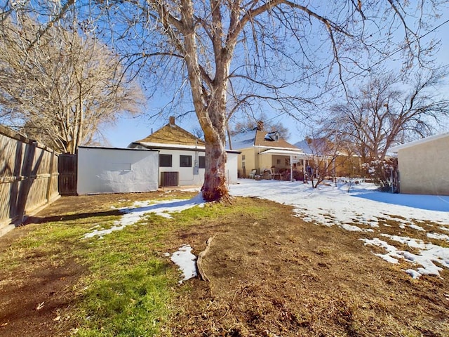 snow covered house featuring a yard and fence