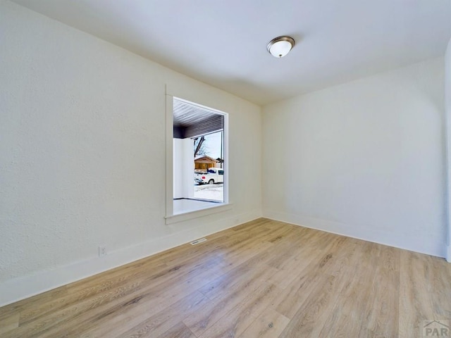 unfurnished room with light wood-style flooring and baseboards