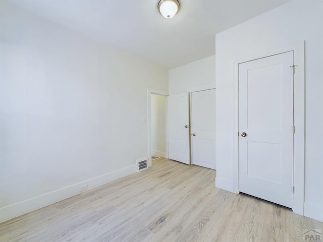 unfurnished bedroom featuring light wood-type flooring, visible vents, and baseboards