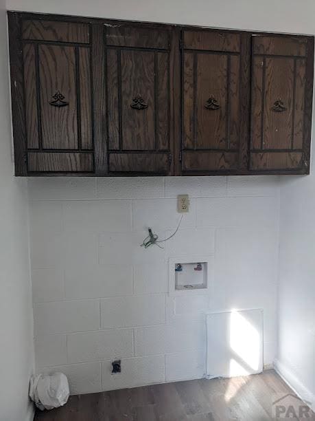 laundry room featuring washer hookup, cabinet space, and wood finished floors