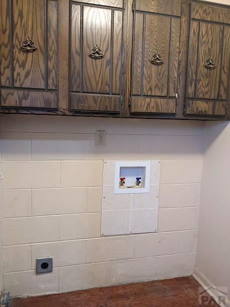 clothes washing area featuring hookup for a washing machine, concrete block wall, cabinet space, and electric dryer hookup