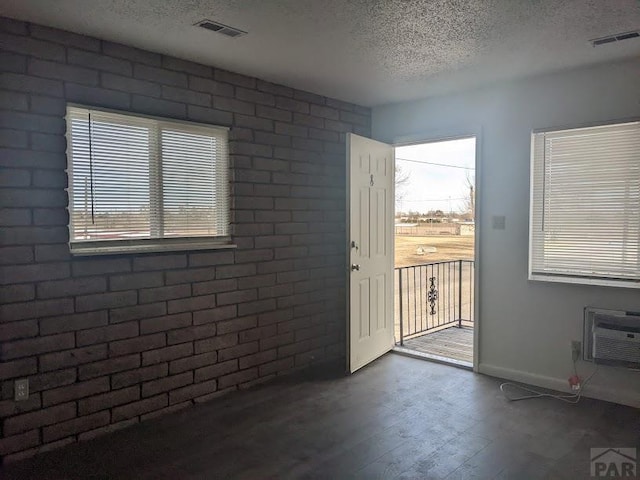 doorway to outside with baseboards, visible vents, dark wood finished floors, a textured ceiling, and a wall mounted AC