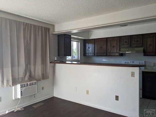 kitchen featuring dark wood finished floors, a wall mounted AC, dark brown cabinetry, range, and under cabinet range hood