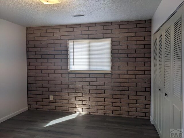 interior space featuring baseboards, visible vents, dark wood-style floors, a textured ceiling, and a closet