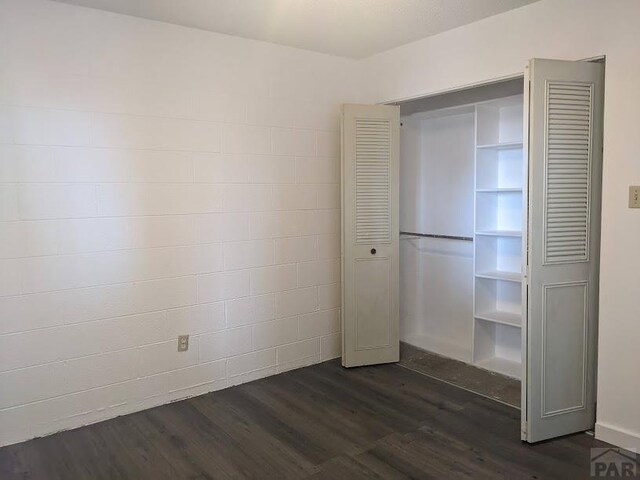 unfurnished bedroom with dark wood-style floors and a closet