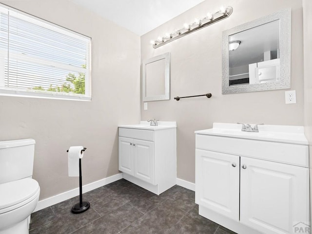 2619 7th Ave, Pueblo, CO 81003 - full bath with two vanities, toilet, baseboards, and tile patterned floors